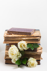 Old books pile with white flowers flowers on white chair background with copy space