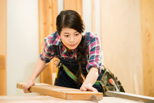 young female carpenter cutting wood