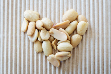 peeled peanuts in a heart shape on corrugated cardboard