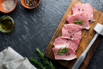 Meat. Raw pieces of pork with rosemary and pepper on a black background. Selective focus. Top view. Place for text.