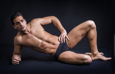 Fototapeta na wymiar A handsome latin young man lying naked on the floor, wearing only underwear. Muscular build