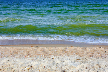 Soft sea ocean waves wash over golden sand background. Beautiful seascape with water splashes. Selective focus on the splash