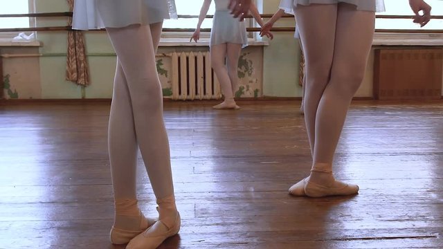 Girls stand in third position and begin to dance in ballet classroom.