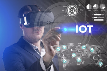 Business, Technology, Internet and network concept. Young businessman working in virtual reality glasses sees the inscription: IOT