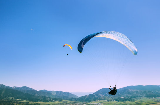 Flying paragliders in sky
