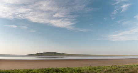 Lake and hills under a blue sky with clouds