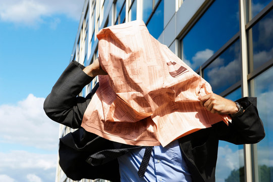 Businessman with newspaper over face