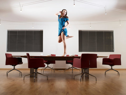 Young woman dancing on boardroom table
