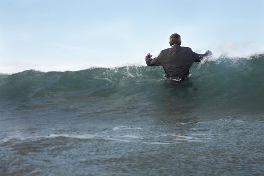 A businessman wading into the sea