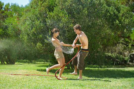 Teenagers playing with water hose
