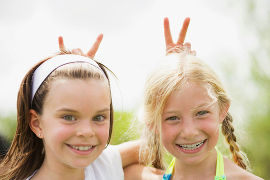 2 young girls smiling giving rabbit ears