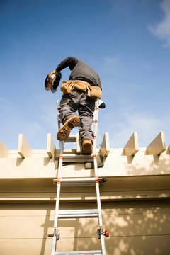 Workman on ladder to roof