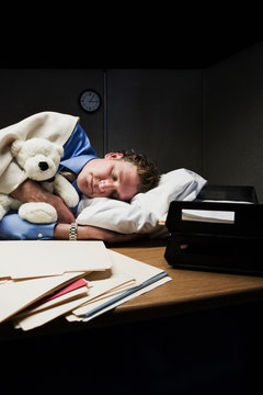 Man with stuffed animal sleeping on desk