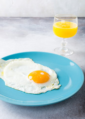Fried egg on blue plate and orange juice. Healthy breakfast concept with copy space.