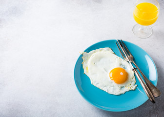 Fried egg on blue plate and orange juice. Healthy breakfast concept with copy space.