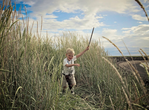 Boy playing with sword in wheat field