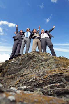 Businessmen cheering on cliff