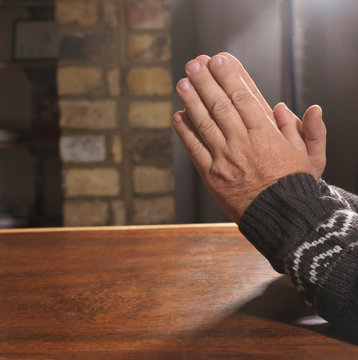 Older man with hands clasped in prayer