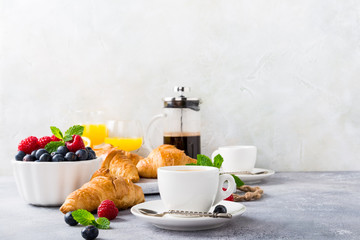 White cups of coffee and croissants on light gray background, selective focus. Healthy breakfast...