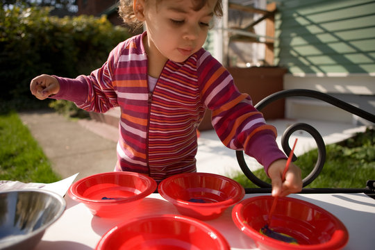 Toddler girl playing with paints outside