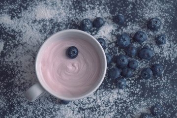 Yoghurt and blueberries lie on a black chalkboard