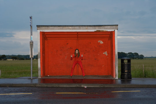 Teenage girl wearing red clothes at red bus stop