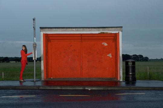 Teenage girl wearing red clothes at red bus stop