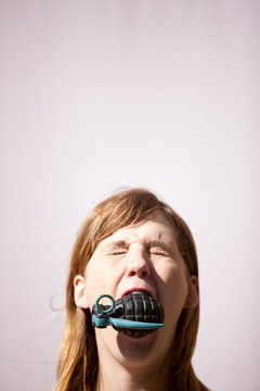 Woman with hand grenade in mouth
