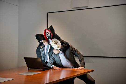 Businessmen in masks fighting over laptop
