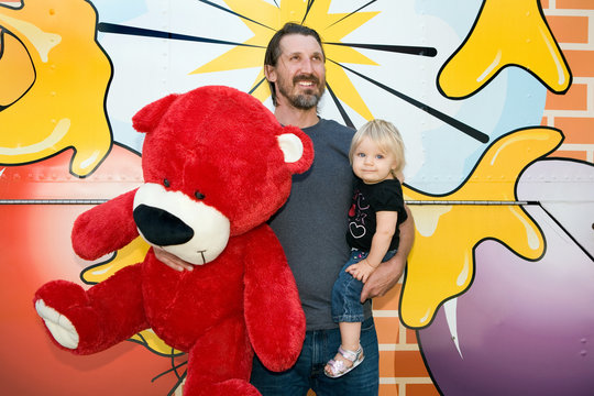 Man holding large teddy bear and son