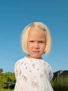 Young girl frowning outside, portrait