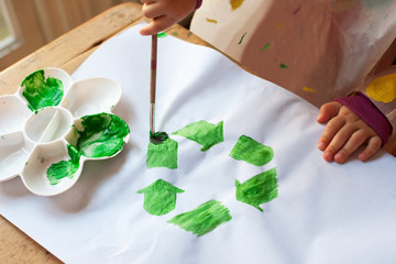 Child painting green recycling symbol