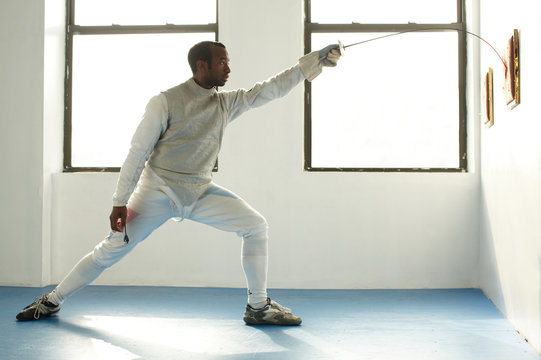 Male fencer holding foil to target, side view