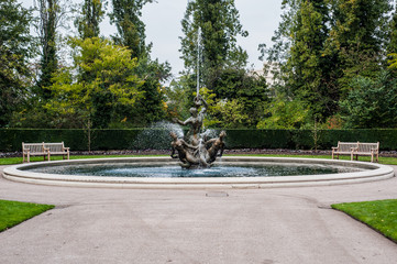 Fountain in London Park, squirting water all the way with benches on sides