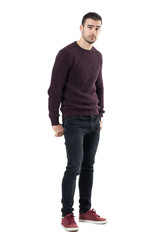 Naklejka premium Cool seductive young casual man with hands in back pockets looking at camera. Full body length portrait isolated over white studio background.