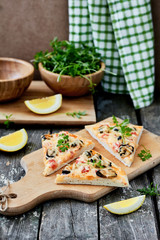 Fresh delicious Italian Seafood pizza slice with mussels,tomatoes on a cutting board. vertical