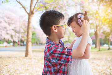Asian boy putting flower on his sister's hair