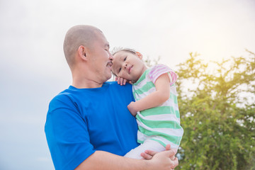 Asian father holding his daughter in park