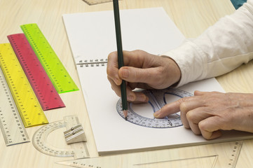 Una persona dibuja un circulo con la ayuda de un transportador de angulos