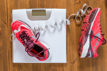 Women's running shoes and scales on the wooden floor view from above
