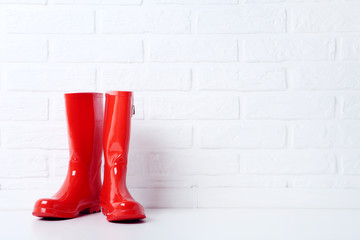 Red rubber boots on brick wall background