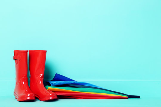 Red rubber boots with umbrella on a green background