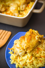 Spicy chicken curry with rice on a dark background. Chicken and rice casserole in a backing dish. Chicken and rice on a blue plate. Healthy dinner.