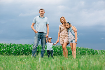 Happy family of four walking through the field. Mother father son daughter Smiling and laughing. Girl with parents and her little  brother