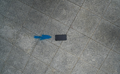 Top view of mobile phone isolated next to blue arrow painted on asphalt street, can be used as background or pattern