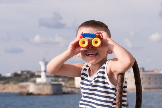 smiling small boy looking into the distance through binoculars