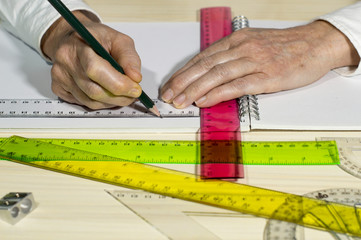 Una persona dibuja una linea recta con ayuda de una regla