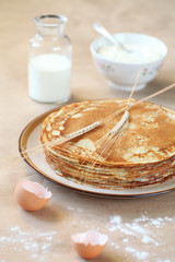 Blini - traditional Russian pancakes - on beige plate, on light beige background.