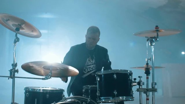Young rock and roll drummer showing his skills with drums in slowmotion live underground
