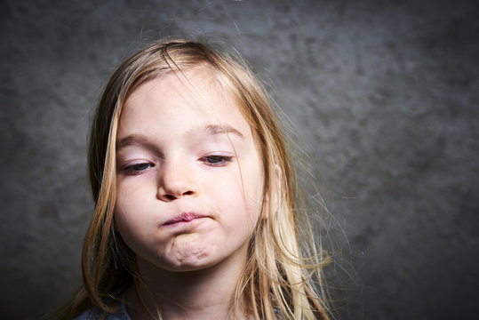 little child blond girl making faces with gray grunge wall background